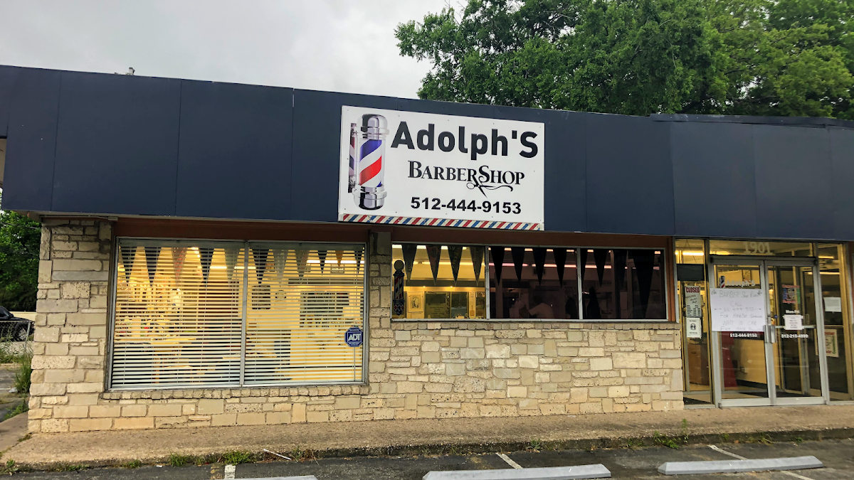 Adolph's Barber Shop storefront with a barber pole sign and phone number
