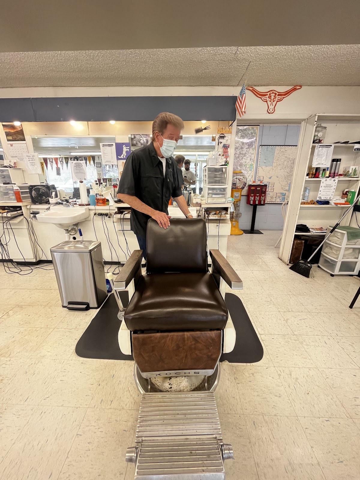 A vintage leather barber chair beneath a Texas longhorn decoration and American flag
