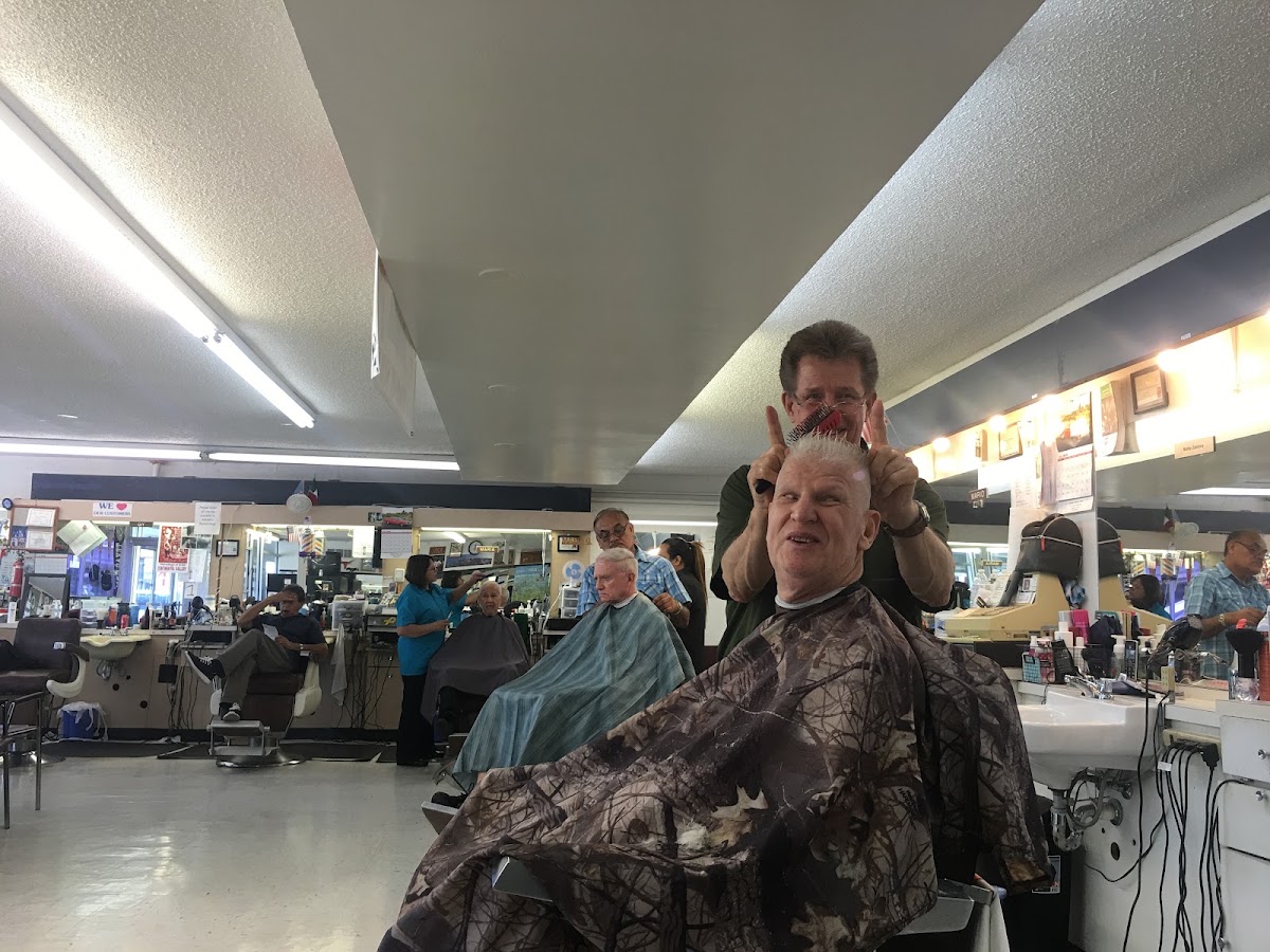 A barber and customer sharing a laugh mid-haircut at Adolph's Barber Shop