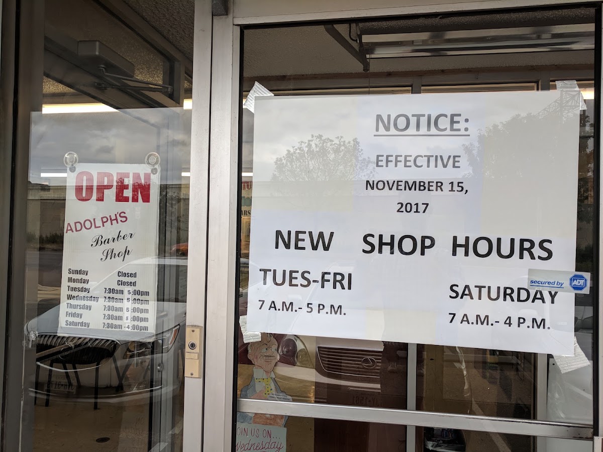 The front door of Adolph's Barber Shop with the OPEN sign and hours posted