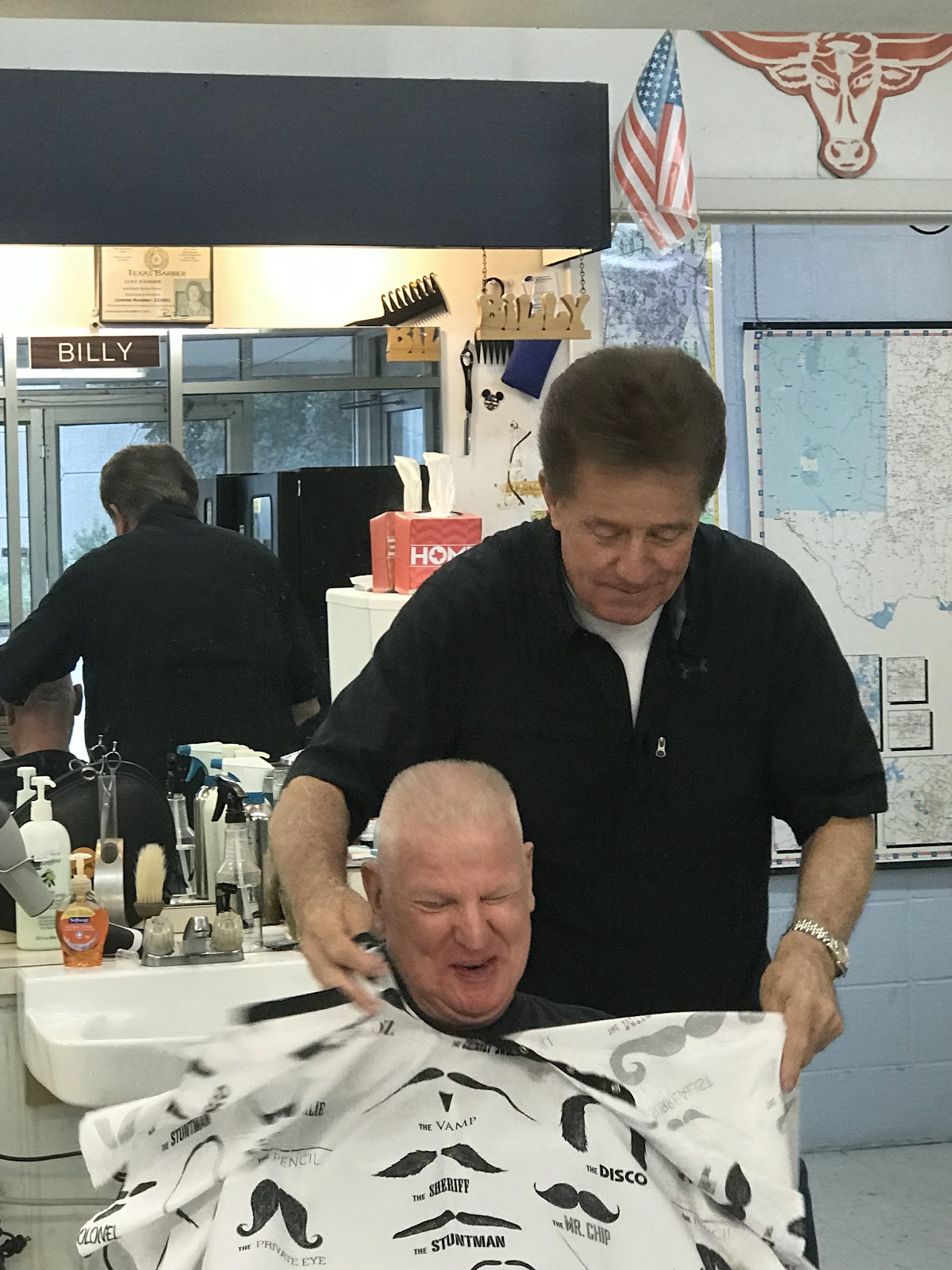 Barber Billy finishing a haircut, with a framed Texas Barber license visible on the wall